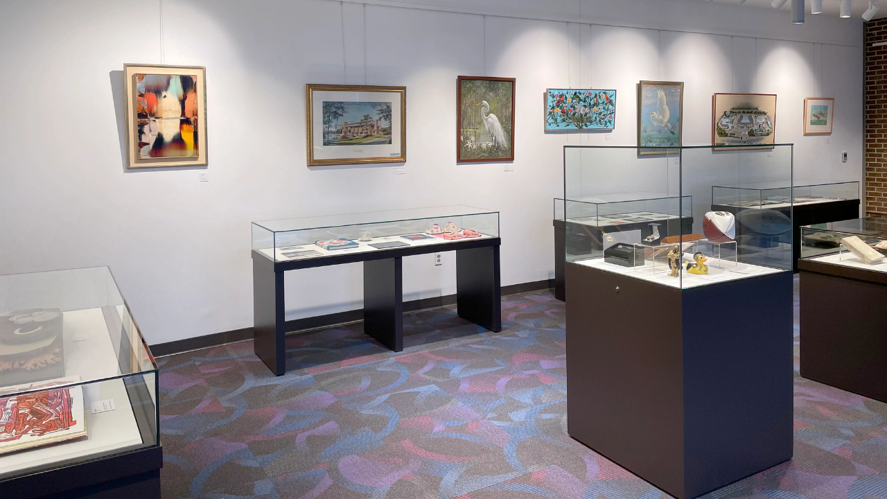 Variety of glass exhibit cases with art displayed on wall